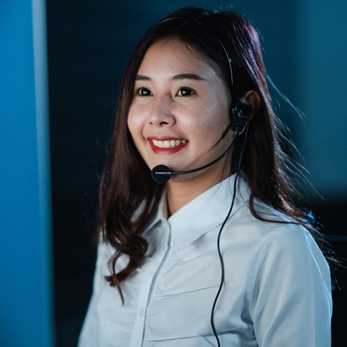 Millennial Asia young call center team or customer support service executive using computer and microphone headset working technical support in late night office. Telemarketing or sales job concept.